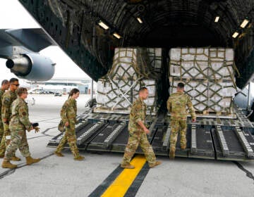 Crew members walk up a ramp to where boxes of baby formula are stacked.