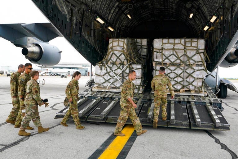 Crew members walk up a ramp to where boxes of baby formula are stacked.