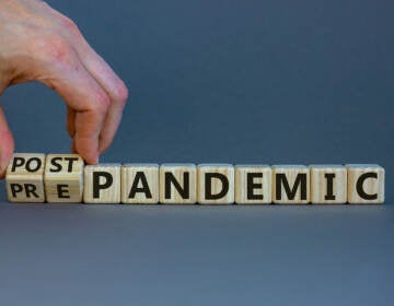 Hand turns cubes and changes the words 'pre-pandemic' to 'post-pandemic'.