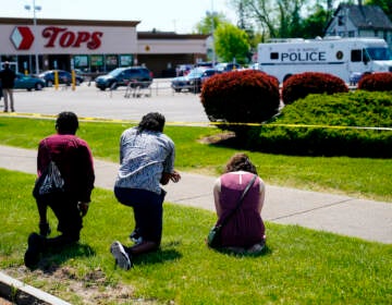 People pray outside the scene of a mass shooting at a supermarket