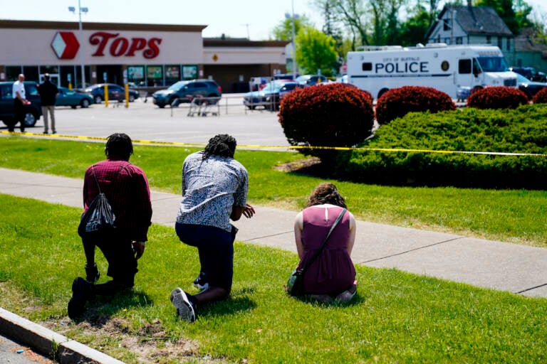 People pray outside the scene of a mass shooting at a supermarket