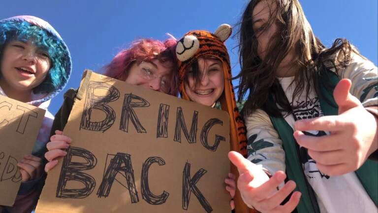 Students are seen holding. a sign that says ''Bring Back''