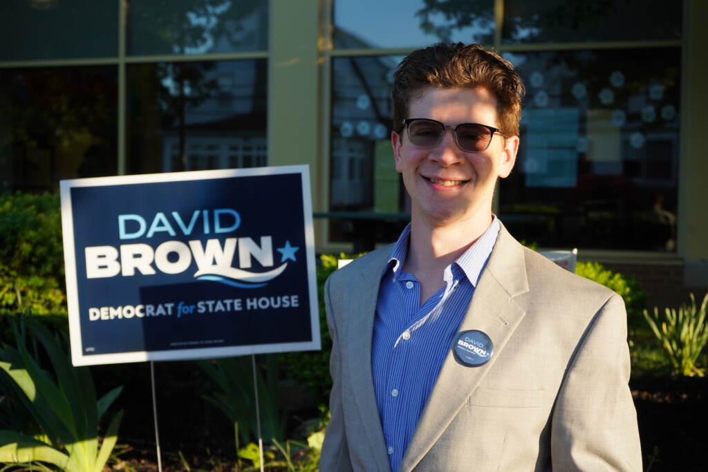 David Brown stands in front of a campaign sign