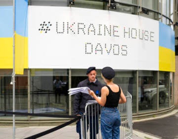 A security guard talks to a women in front of the Ukrainian House alongside the World Economy Forum in Davos, Switzerland, Sunday, May 22, 2022. The annual meeting of the World Economy Forum is taking place in Davos from May. 22 until May. 26, 2020.