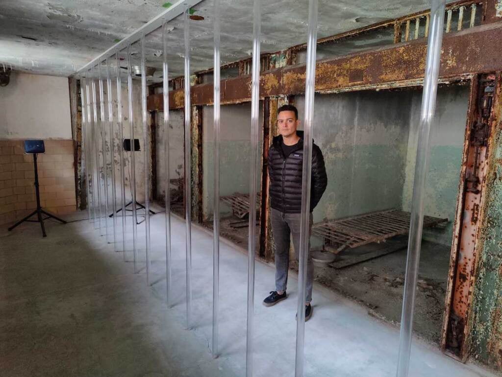 Artist Menjivar stands behind the bars that are part of his exhibition at Eastern State Penitentiary.