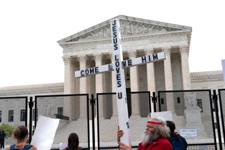 File photo: A demonstrator holding a cross protests outside of the U.S. Supreme Court, Thursday, May 5, 2022, in Washington.