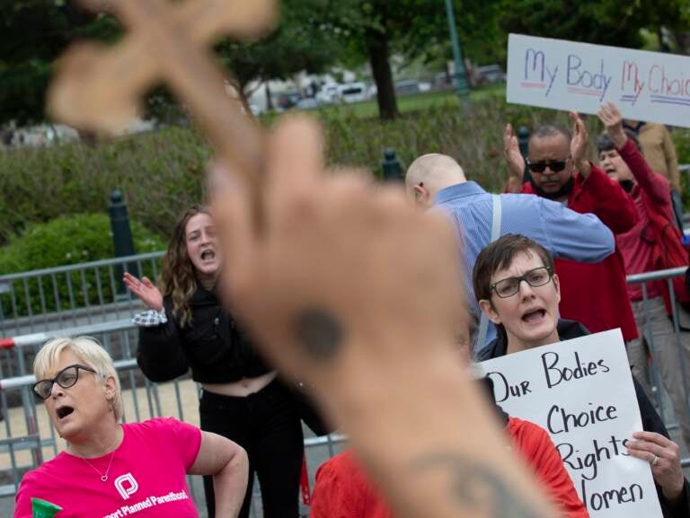 Nate Darnell holds a cross while surrounded by chanting abortion-rights demonstrators outside the U.S. Supreme Court on Thursday in Washington, D.C. (Tom Brenner/Getty Images)