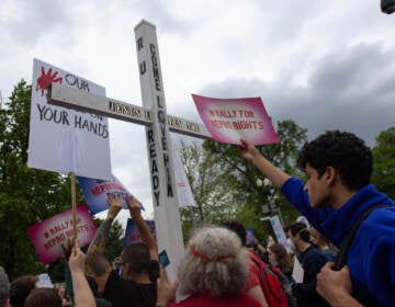 A counter-protestor holds a large cross during a youth pro-abortion rights rally outside of the Supreme Court in Washington, D.C., on May 5, following the leak of a draft Supreme Court opinion to overturn Roe v. Wade.