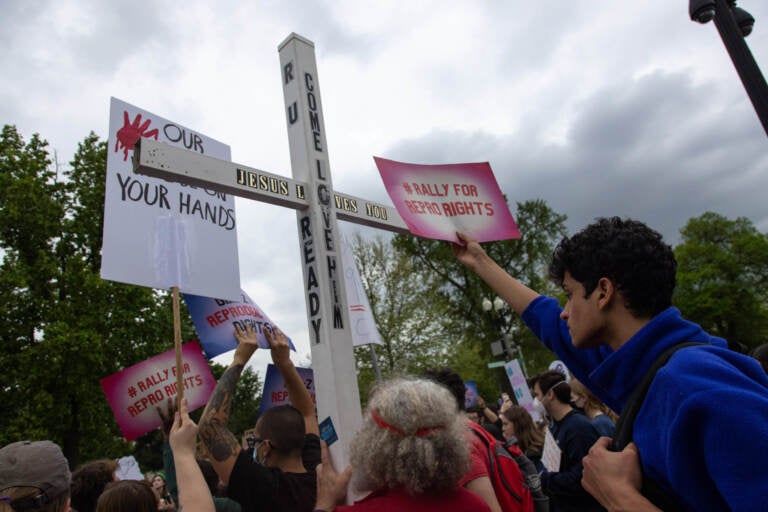 A counter-protestor holds a large cross during a youth pro-abortion rights rally outside of the Supreme Court in Washington, D.C., on May 5, following the leak of a draft Supreme Court opinion to overturn Roe v. Wade.