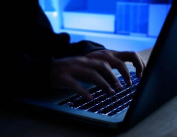 Close-up of someone's hands typing on a laptop in a dark room.