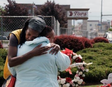 Two people embrace in front of a memorial to victims of the Buffalo supermarket shooting.