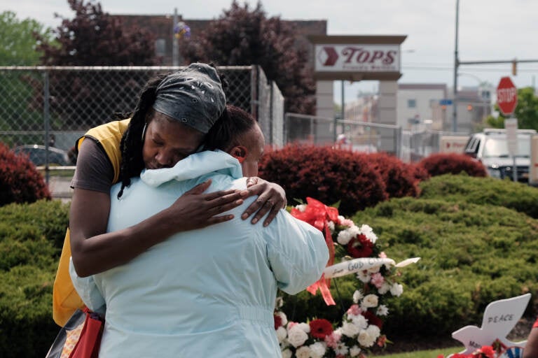 Two people embrace in front of a memorial to victims of the Buffalo supermarket shooting.