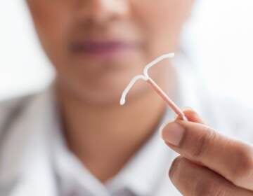 A doctor holds up an IUD