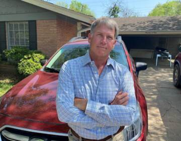 West Hansen stands in front of a red car, with his arms folded, posing for the photo.