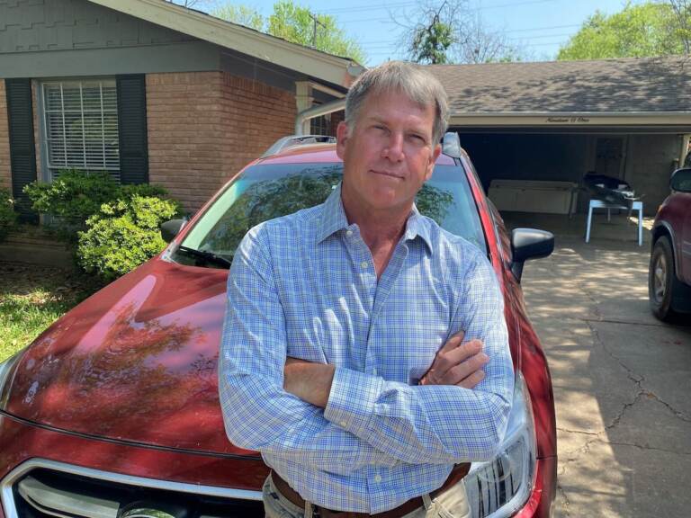 West Hansen stands in front of a red car, with his arms folded, posing for the photo.