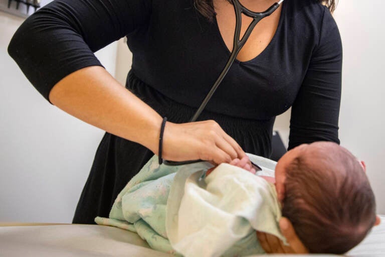 A pediatrician examines a newborn baby