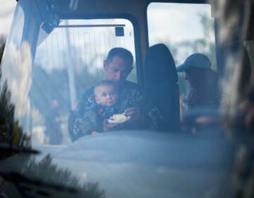 A man feeds a baby on a bus full of evacuees in Ukraine