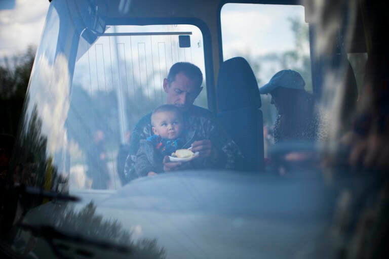 A man feeds a baby on a bus full of evacuees in Ukraine