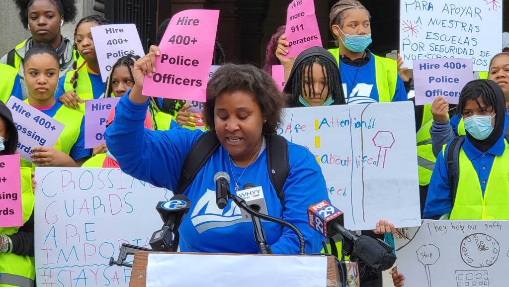 Renee Sanders holds up a sign while speaking at a protest