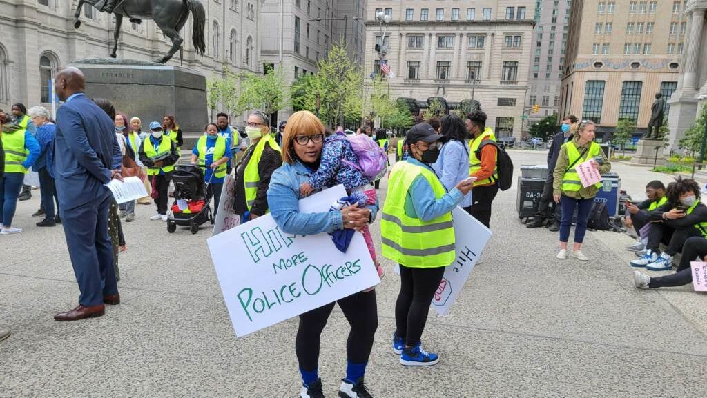 Ashley Harris holds a child and protest sign calling for more police officers