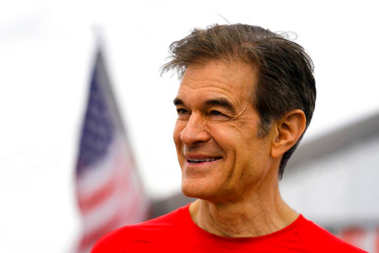 Close-up of Mehmet Oz, who is smiling, with an American flag in the background.