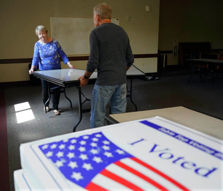 Cecelia Peterson and Dan Pollock move a table at a polling place