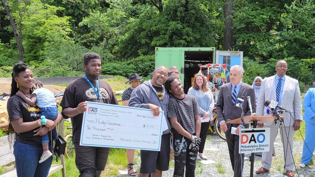 Members of Philly Pumptrack pose together with a check showing their microgrant from the DA's Office.