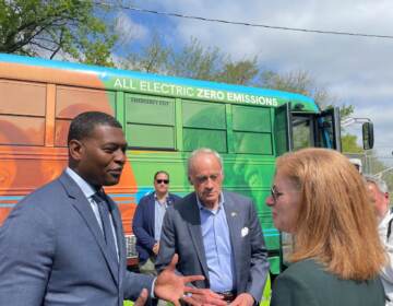 EPA chief Michael Regan (left) talks with U.S. Sen. Tom Carper and an unidentified woman at The Warehouse for teens in Wilmington. Behind them is the center's electric bus.