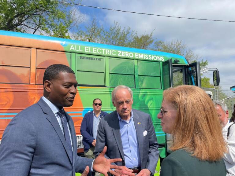 EPA chief Michael Regan (left) talks with U.S. Sen. Tom Carper and an unidentified woman at The Warehouse for teens in Wilmington. Behind them is the center's electric bus.