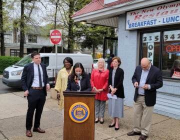 Business members and officials gather outside New Olympia House Restaurant to celebrate small biz week.