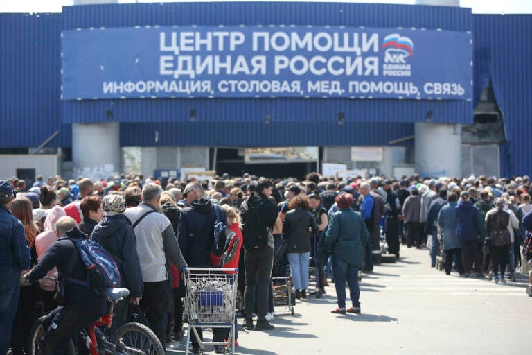 Local civilians line up to get humanitarian aid distributed in the United Humanitarian Center in Mariupol