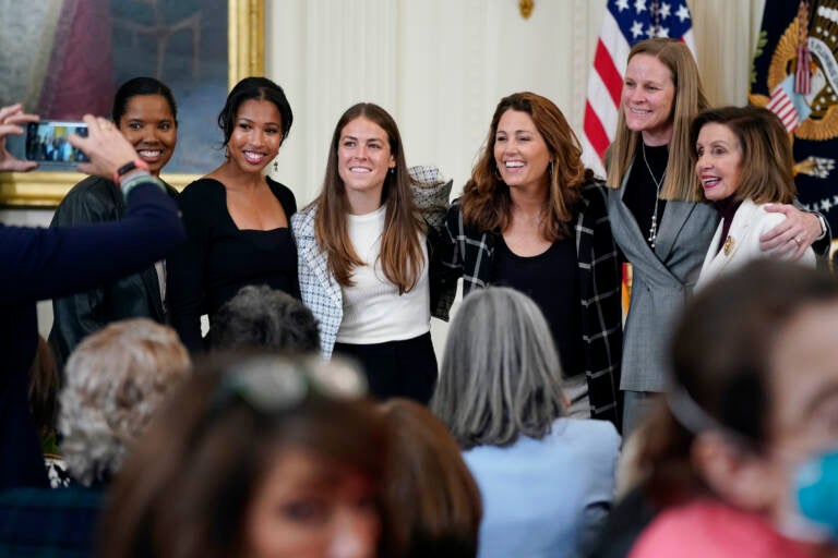 FILE  - Former members and members of the U.S. Women's National soccer team, from left,  Briana Scurry, Margaret 'Midge' Purce, Kelley O'Hara, Julie Foudy, and Cindy Parlow Cone, President of U.S. Soccer, pose for a photo with House Speaker Nancy Pelosi of Calif., before an event to celebrate Equal Pay Day and Women's History Month in the East Room of the White House, Tuesday, March 15, 2022, in Washington. The U.S. Soccer Federation reached milestone agreements to pay its men's and women's teams equally, making the American national governing body the first in the sport to promise both sexes matching money. (AP Photo/Patrick Semansky, File)