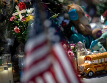 A toy yellow school bus is in focus, with a blurry American flag in the foreground.