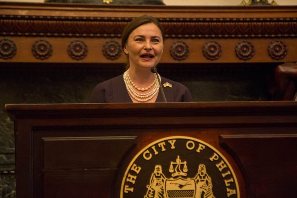 Iryna Mazur speaks from a podium at City Hall