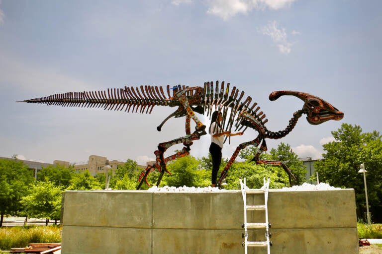 Artist Marianela Fuentes stands in the ribcage of her sculpture, ''Alpha Sacred Beings (The Order of Creation),'' mounted on a six foot concrete plinth in Philadelphia Navy Yard. (Emma Lee/WHYY)