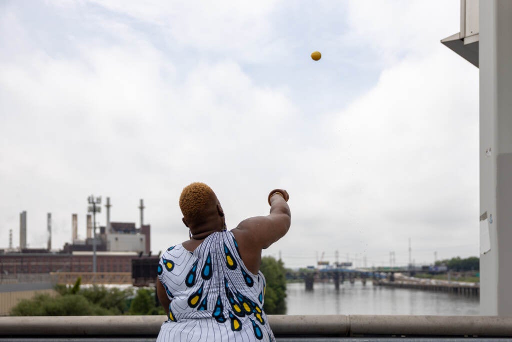 Nikki Powerhouse throws fruit into the Schuylkill River as an offering to Oshun during the 2022 Odunde Festival.