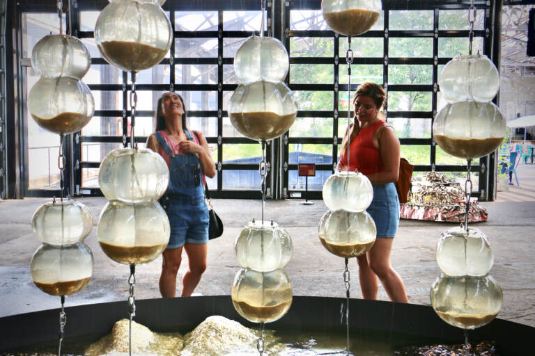 Cristina Conyers (left) and Jazmin Hurtado, visitors to Philadelphia from Los Angeles, check out Jean Shin's ''Freshwater'' at the Cherry Street Pier. (Emma Lee/WHYY)