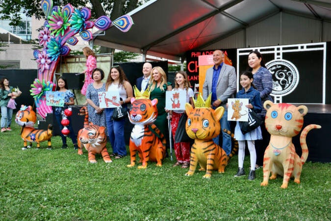 A group of students pose with their designs and the lanterns made from their designs.