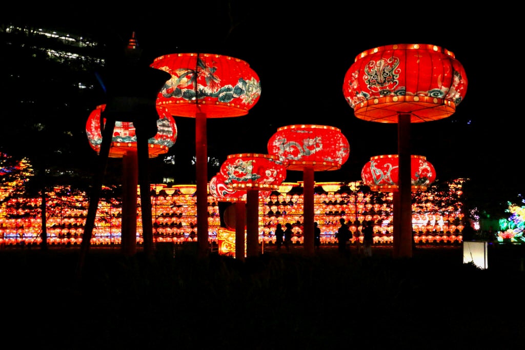 Red-colored standing lanterns are glowing in the dark, with more lights visible behind them.