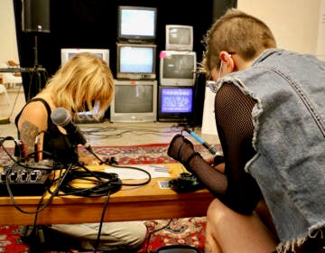 Elissa Anderson (left) and  Jackie Milestone of the Sound Museum Collective work on the broadcast lounge that is part of thier exhibit at the Asian Arts Initiative. (Emma Lee/WHYY)