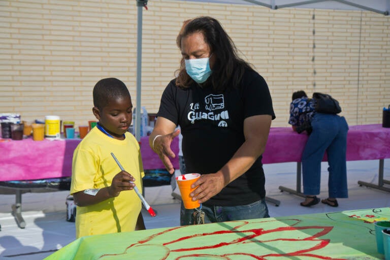 Mural Arts’ Cesar Viveros (right), worked with the North Philadelphia community to create a bus wrap celebrating La Guagua 47 Community Film and Arts Project on June 24, 2022. (Kimberly Paynter/WHYY)