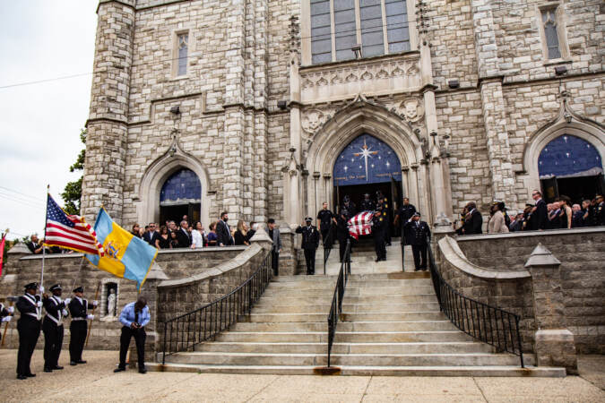 Officers carry a casket draped with the American flag down the steps of the church.