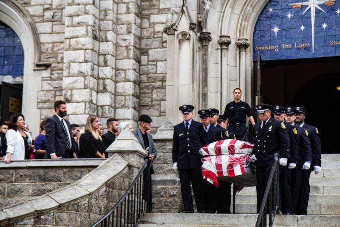 Officers carry a casket draped with the American flag down the steps of the church.