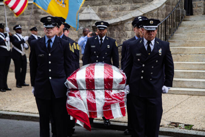 Officers carry a casket draped with the American flag.