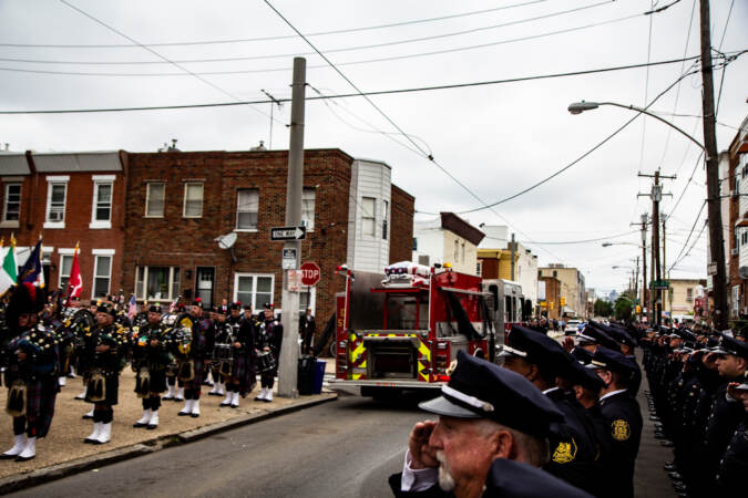 Members of the fire department salute as a fire truck passes through the streets.