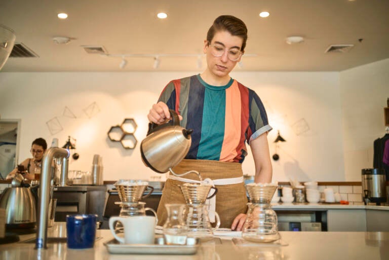 Steph Achter pours water into a glass carafe at a coffee shop