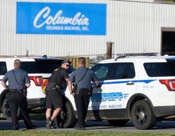 Police stand near where a man opened fire at a business, killing three people before the suspect and a state trooper were wounded in a shootout, according to authorities, in Smithsburg, Md., Thursday, June 9, 2022. The Washington County (Md.) Sheriff's Office said in a news release that three victims were found dead at Columbia Machine Inc. and a fourth victim was critically injured. (AP Photo/Steve Ruark)