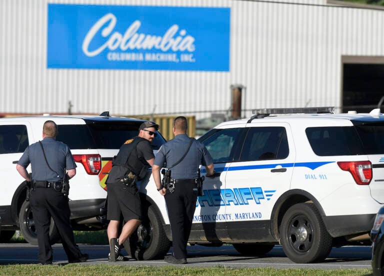 Police stand near where a man opened fire at a business, killing three people before the suspect and a state trooper were wounded in a shootout, according to authorities, in Smithsburg, Md., Thursday, June 9, 2022. The Washington County (Md.) Sheriff's Office said in a news release that three victims were found dead at Columbia Machine Inc. and a fourth victim was critically injured. (AP Photo/Steve Ruark)