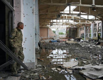 A Ukrainian serviceman looks at the ruins of the sports complex of the National Technical University in Kharkiv, Ukraine, Friday, June 24, 2022, damaged during a night shelling. The building received significant damage. A fire broke out in one part but firefighters managed to put it out. (AP Photo/Andrii Marienko)