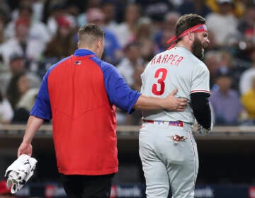 Philadelphia Phillies' Bryce Harper, right, reacts towards San Diego Padres' Blake Snell after being hit by a pitch from Snell, as he walks off the field with a trainer during the fourth inning of a baseball game Saturday, June 25, 2022, in San Diego. (AP Photo/Derrick Tuskan)
